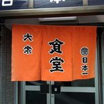 大衆食堂 日本一 - お店の暖簾です。オレンジ色に黒字で大衆　食堂　日本一　と書かれていますね。シンプルな暖簾でいい感じです。