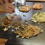 はなまる - オタフクノのお好み焼きソースと焼きそばソースをブレンドしたものを掛けて仕上げていきます。