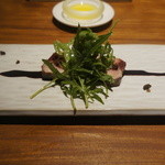 エニェ - 戻りカツオのプランチャ、ルッコラセルバチコ、ケーパ、カシスソース