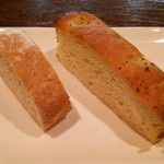 アルモニコ - 2種類のパンは何れも自家製。左は全粒扮のバゲット、右はジャガイモ、アンチョビなどを練り込んだフォカッチャです。 