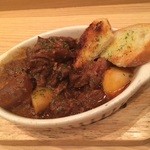 匠屋 あいべ - オープン時から絶やさず継ぎ足す牛スジ煮込み ガーリックトーストを添えて