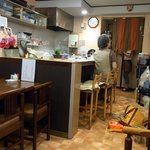 家庭料理　花 - 店内の風景です。入口付近からお店の奥を撮っています。手前は４人掛けのテーブル席が３つあります。そして２人掛けのテーブル席が１つです。カウンター席の向かいは調理場となっています。