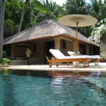 Amankila - プールから部屋を臨む。パラソル、チェア、椰子、白い花とビラ