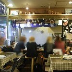 お好み鉄板　炎屋 - 左に大きな鉄板があり、頭上の棚には福助人形やマトリョーシカも飾られています