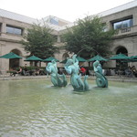 Museum Café - 噴水がある池の周りにパラソル付きのテーブルがある。