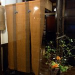 酒盃 - 店内に入ると旧家の玄関のようになっています。 ここにも粋な暖簾が掛かっていますね。 そして、この場所にマッチした植物も置いてあります。 ここで靴を脱いで個別の下駄箱に靴を入れて店内に入ります。 予約し