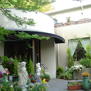 A detached Restaurants surrounded by flowers and greenery on a cobblestone alley in Kitano, Kobe