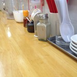 金田家 - カウンター（一部）と卓上調味料。左右にお客さんがいたのでここまでしか撮れなかった。