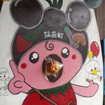 パン工房 - ｢食の都ちくぜん」のマスコットキャラクターちくちゃんと記念撮影♪
      黒大豆「筑前クロダマル」を頭に、なす、きゅうり、しいたけ、いちご、米が盛り込まれ、体はトマト、梨のポシェットをつけた姿らしい（笑）