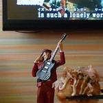 カラオケ ビッグエコー - 料理写真:ロシアンたこ焼き334円とアンガスヤングさま（後ろの画面はビリージョエル）