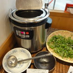 六厘舎 - カウンター横にあるセルフの出汁割り用スープとネギ