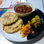 シナモンガーデン - ポル・ロティセット １１５０円(税込)  ロティとは素焼きのみっちりとしたパンみたいなもの。カレーはポーク、あとはボルサンボルと長葱の何か。