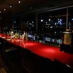 Daininguba Suito - 大橋川の夜景を望むカウンター．窓下に大量のアルコール類が．