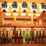 Uogashi Ryourizakoba - 日本酒・焼酎の瓶や提灯がぶら下がっている温かみのある落ち着いた店内