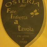 Osteria Del Fate Infretta A Tavola - テーブルクロスの上に敷かれたお店のマーク