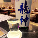 天ぷら酒場 NAKASHO - 日本酒「龍神」(600円)。そのままグラスを皿に戻すと溢れるので、グラスの酒を一口飲み、下皿に溢れた酒の一部をグラスに戻してから撮影した。めんどくさいが酒呑みには"楽しい"シーケンスだ。