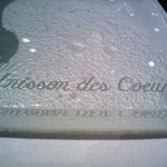 ユニッソン デ クール - ガラスのレイプレートに彫られた店名がテーブルクロスに影で映る