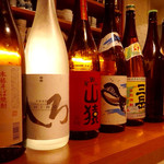 かもふく - 女性スタッフが焼酎の瓶をカウンター上部に並べていた。(理由不明)