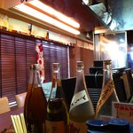 地鶏屋ごくう - 日本酒のビンが並ぶカウンター