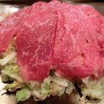 おうさか苑 - 「牛牛玉」（焼いている途中）：お好み焼きからはみ出る程、牛肉がたっぷり♪