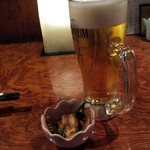 さば銀 - 生ビールにお通しのゲソ炒め。ニンニクが効いて旨い！