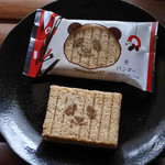 シュガーバターの木 - 袋から出すとこんな感じ。
      シリアル生地にホワイトチョコがサンドされたスイーツだよ。
      目鼻口だけでもパンダに見えるから不思議だよね。