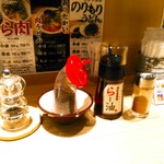 らー油肉つけうどんの南哲 - 卓上にはペッパーミル、白胡麻を黒くなるまで煎ったもの、辛くない方のらー油、一味。