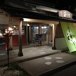 回転寿司割烹 伊達 和さび - 夜のお店の外観（入り口）。かがり火が灯っています。