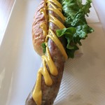 サブマリン - 「ダイナマイト Hot Dog's」縦写しで接写。大きさ、味、歯ごたえ、なにもかもが豪快な、ヤツの名はダイナマイト。店内メニューポップでそう紹介されている。