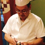 うを徳 - 鮎の手巻きを握る店主こみけんさん