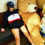 安楽亭 - 待ち合いのベンチで大きな熊のぬいぐるみと寝そべる少女