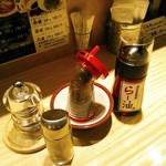 らー油肉つけうどんの南哲 - 卓上にはブラックペッパー、一味、白胡麻を煎った黒胡麻、風味重視で辛くないらー油。