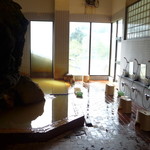 十勝岳温泉 湯元 凌雲閣 - 苔むした岩が張り出す内湯。建物に岩を組み込んだのではなく、もともと岩があった場所を風呂場にしたんだとか