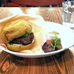 ブリコラージュ ブレッド アンド カンパニー ダイニング・カフェ - 自家製バンズはパンドミ生地にほうれん草ピュレが混ぜ込まれているもの。モチモチ食感。肉肉しいパティの肉汁、甘み旨みが堪らず。バジルソースやピクルスがまたいい。自家製ケチャップをパティにonしても合うよ♪